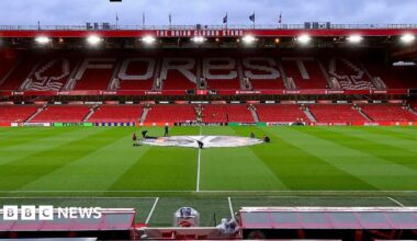 A low shot of the Nottingham Forest home pitch, with a tall, red and white football stand in the background