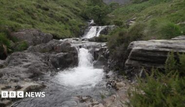 A national park's beauty spot shows a waterfall and rocks surrounded by a pool.