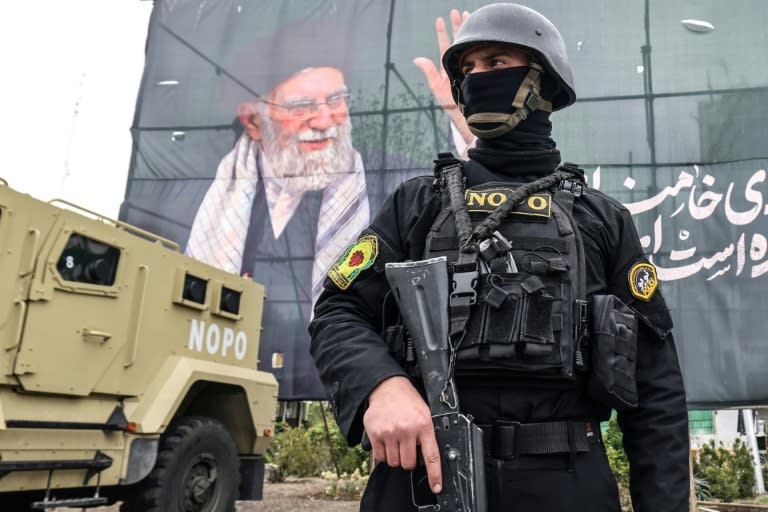 A member of the Iranian security forces stands guard next to a banner honouring Iran's slain supreme leader Ayatollah Ali Khamenei in Tehran (ATTA KENARE)