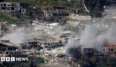 Smoke rises from bombed out buildings.