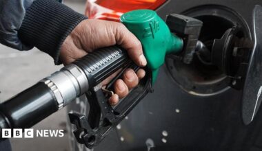 A man topping up his car's fuel using a green petrol pump