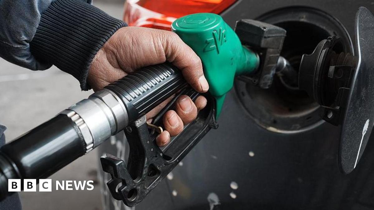 A man topping up his car's fuel using a green petrol pump