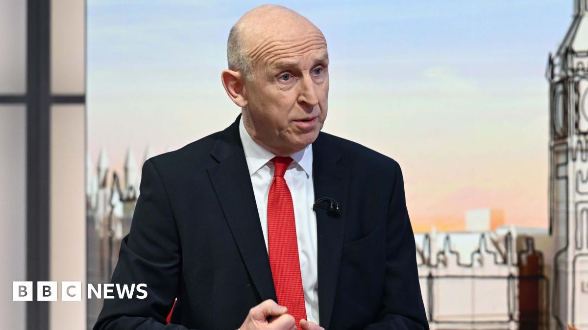 Stock image of a female climber wearing a backpack hanging onto a rock