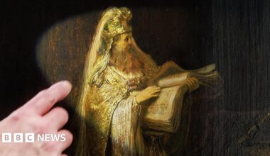 A researcher points at, and points a torch at, the figure of Zacharias from Rembrandt’s Vision of Zacharias in the Temple (1633), which is on an easel