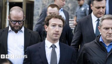 Mark Zuckerberg, wearing a navy suit and grey tie, leaving court in Los Angeles in February, flanked other personnel.