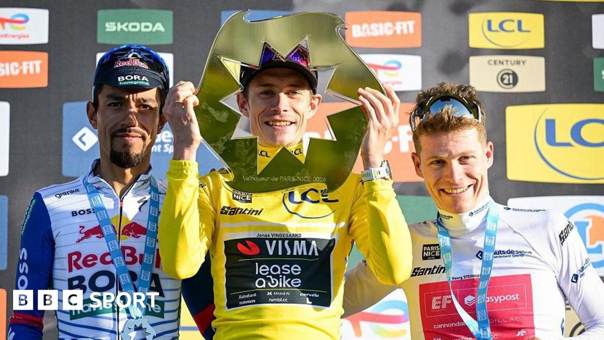 Jonas Vingegaard holds the Paris-Nice trophy in front of his face and stands next to Dani Martinez and Georg Steinhauser