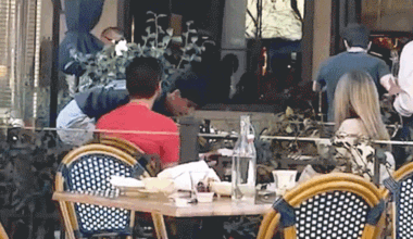 Two men appear to shove and lunge toward each other near an outdoor dining area