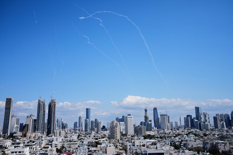 White streaks in a blue sky above a city.