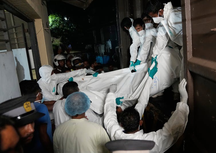 Workers unload bodies of Iranian sailors who died when the IRIS Dena warship sank outside Sri Lanka's territorial waters