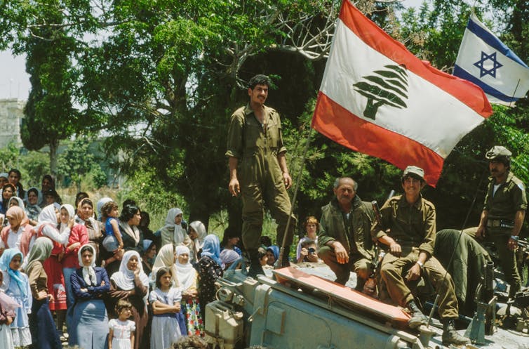 A man stands next to a large flag surrounded by other people