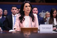 A woman with long dark hair in a pink jacket.