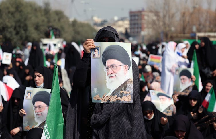 Iranian women hold up pictures of the assassinated supreme leader, Ali Khamenei.