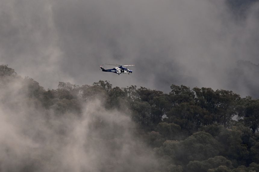 A police helicopter flies over a property during the search for a fugitive linked to the murder of two police officers, in Porepunkah, Australia, on August 28, 2025.