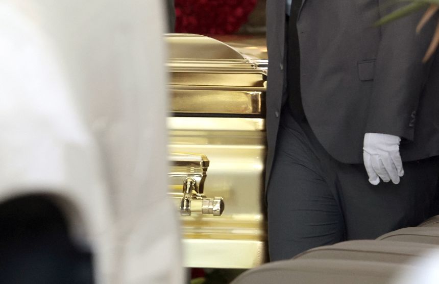 A funeral employee carries the coffin of drug trafficker Nemesio