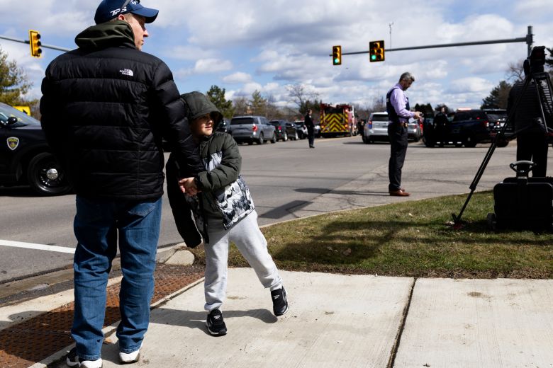 People look on from the sidewalks as law enforcement officers respond near Temple Israel.