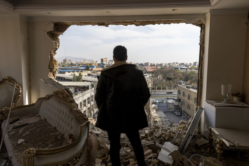 A man stands in a damaged residence on March 14, 2026, in Tehran, Iran.