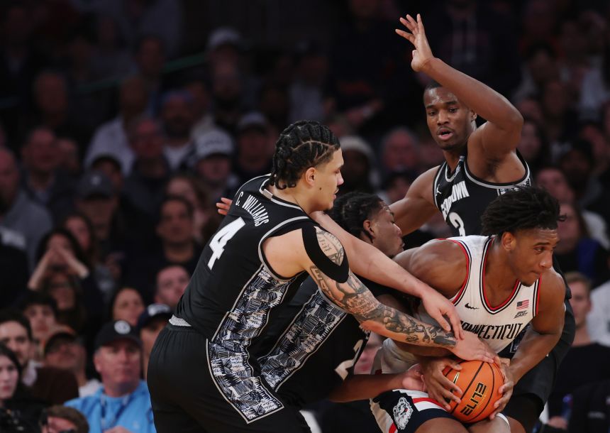 Tarris Reed Jr. #5 of the Connecticut Huskies controls the ball as Caleb Williams #4, Malik Mack #2, and Vince Iwuchukwu #3 of the Georgetown Hoyas defend during the first half of the 2026 Big East Men's Tournament - Semifinal game at Madison Square Garden in New York City on March 13, 2026.
