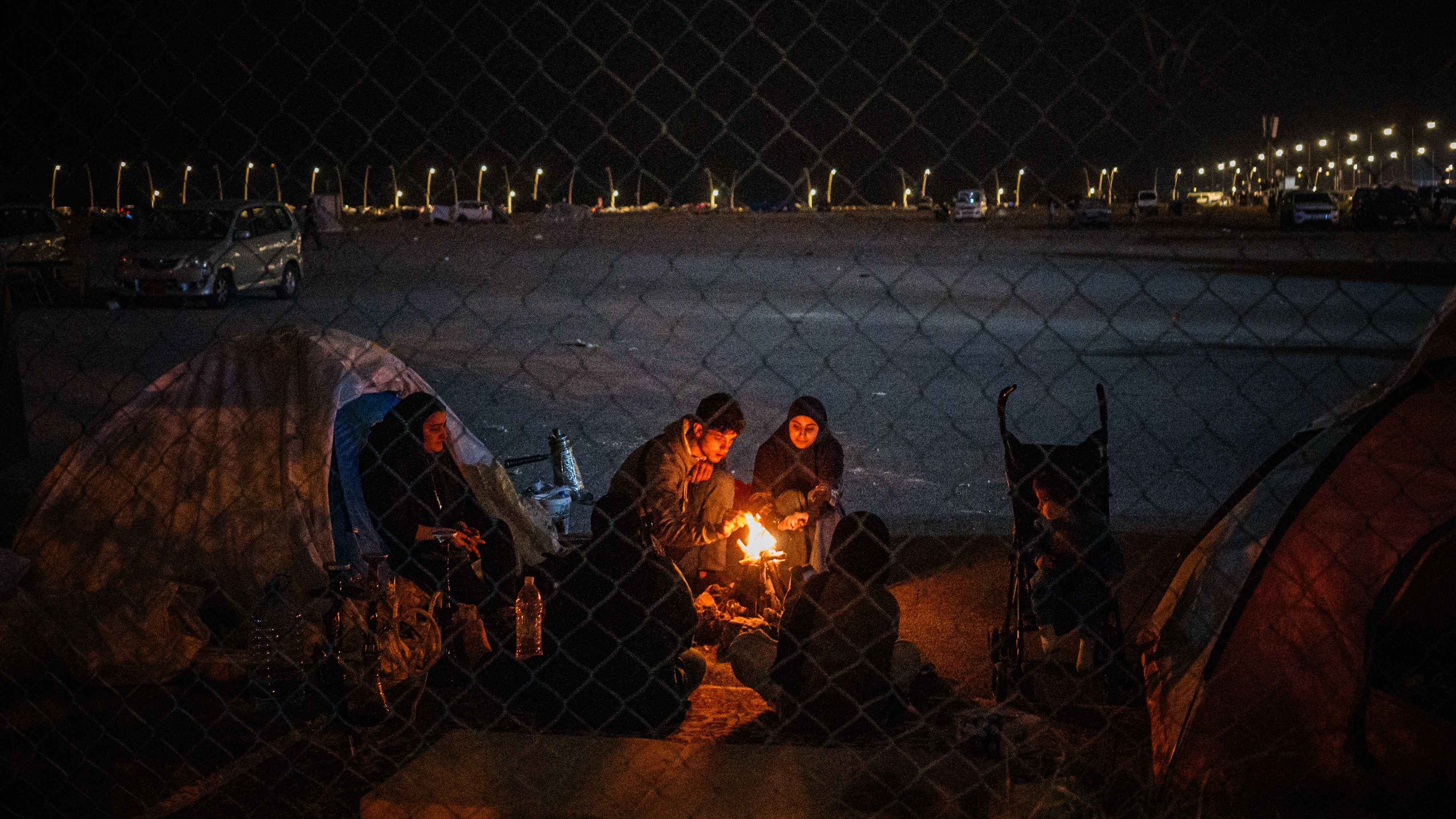 Displaced family members sit around a fire outside their tent along the seafront in Beirut on March 18, 2026. Lebanon was drawn into the Middle East war on March 2 when militant group Hezbollah launched rockets towards Israel to avenge the killing of Iran's supreme leader Ayatollah Ali Khamenei. Israel responded with intense strikes on Lebanon that have killed at least 968 people and displaced over a million, according to local authorities, and by launching ground operations in the south. (Photo by DIMITAR DILKOFF / AFP via Getty Images)