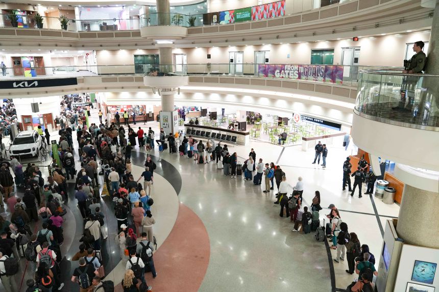 An officer looks on as travelers stand in long lines at Hartsfield-Jackson Atlanta International Airport on Monday.