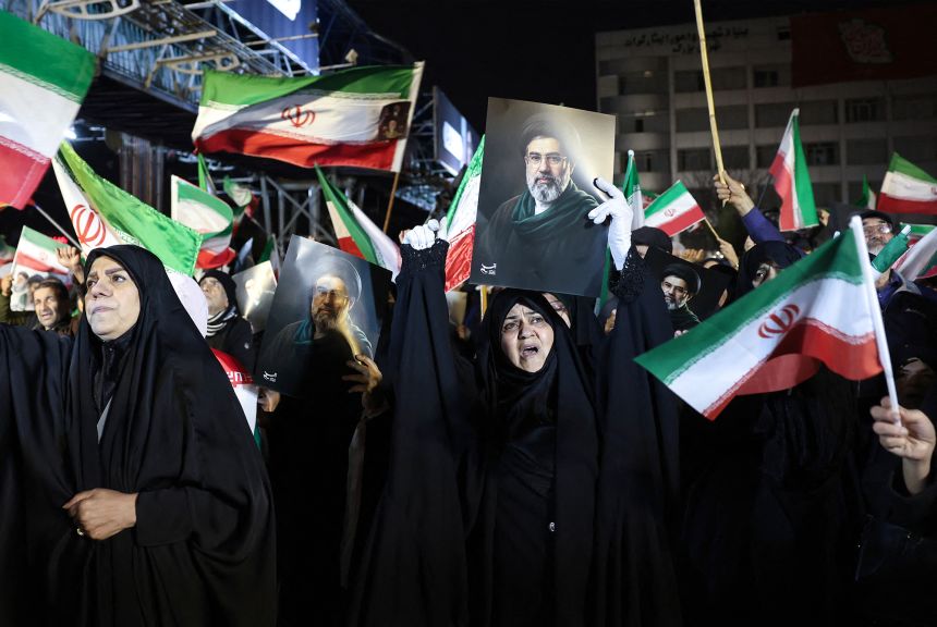 People wave national flags and hold portraits of Iran's supreme leader Mojtaba Khamenei as they march in support of the Iranian armed forces in central Tehran.