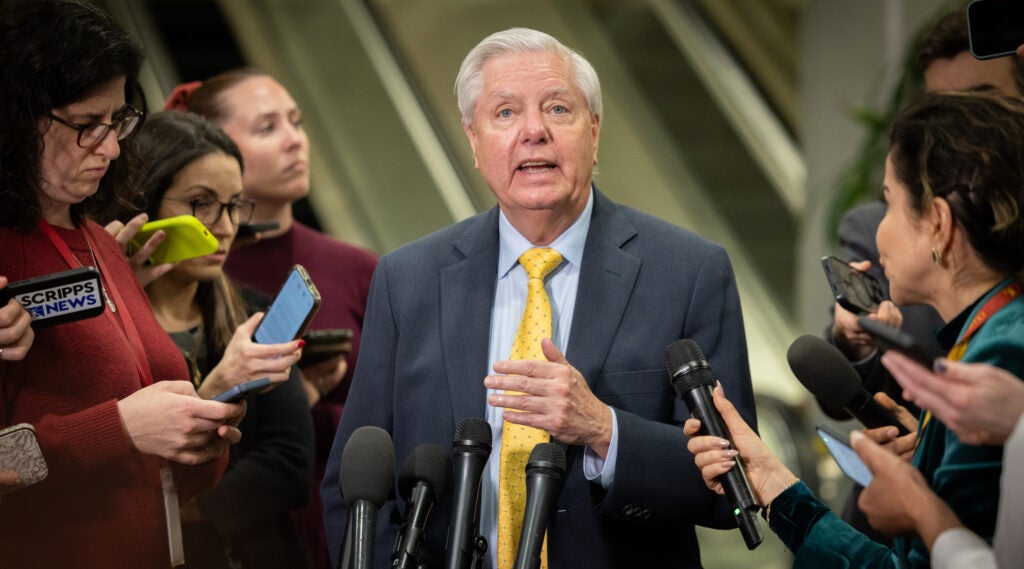 A photo of Graham speaking with reporters.