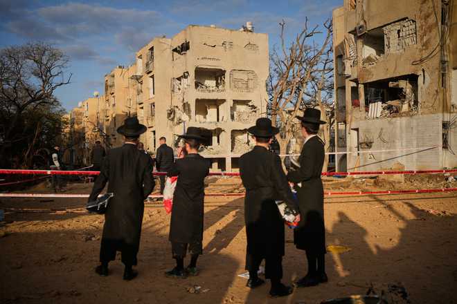 People look at residential buildings heavily damaged by an Iranian missile strike in Arad, southern Israel, Sunday, March 22, 2026.