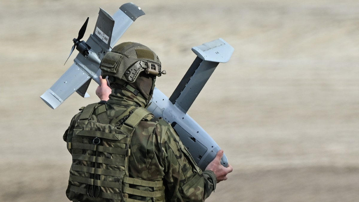 Polish soldier holding an AS3 Surveyor interceptor drone from the U.S. MEROPS counter-drone system during a live-fire exercise in Poland.