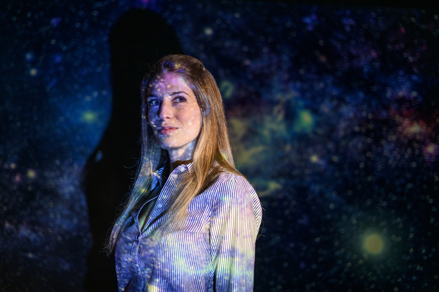 Northeastern University physics professor Jacqueline McCleary stands against a backdrop of stars.