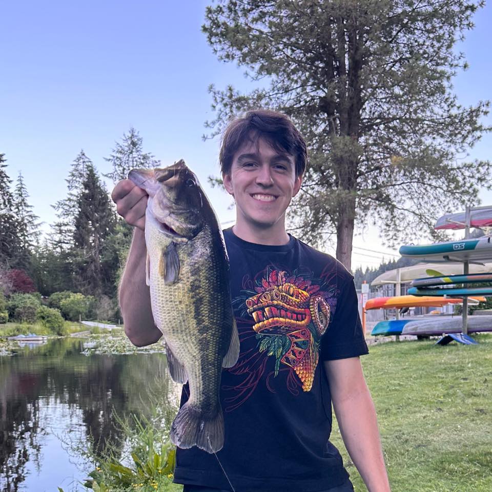Sidney Mohorovich holding up a large bass fish he caught.