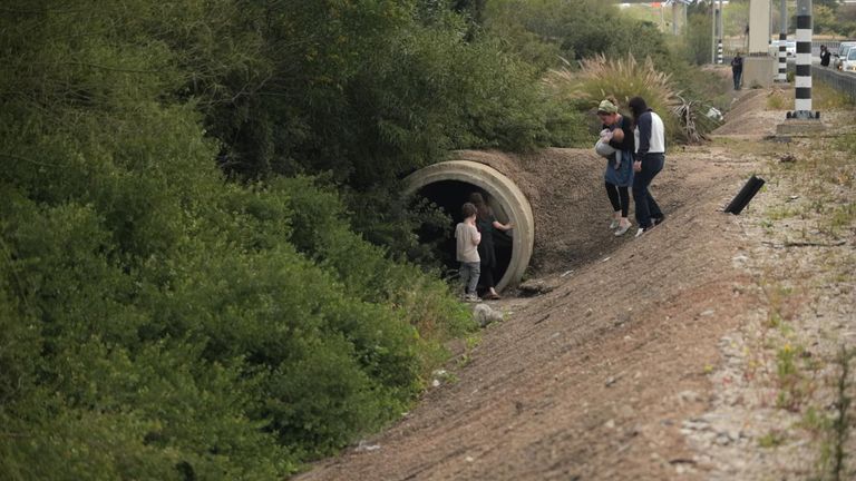 A woman with a baby takes cover by the side of the road