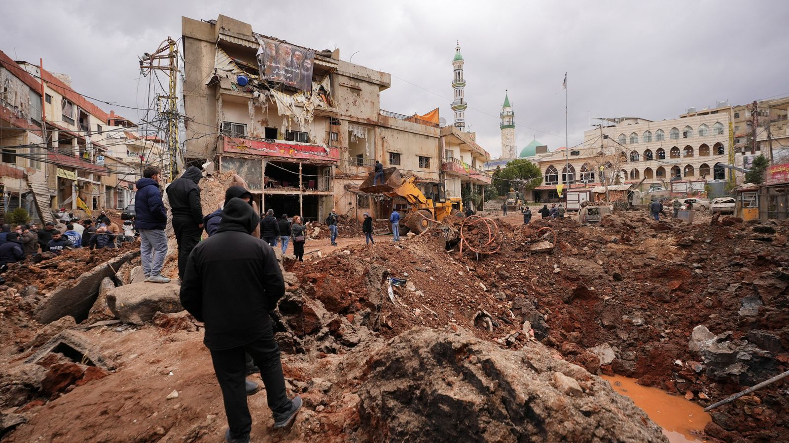 People inspect the damage where Israel's military carried out an airborne operation that dropped troops in Nabi Chit. Pic: Reuters