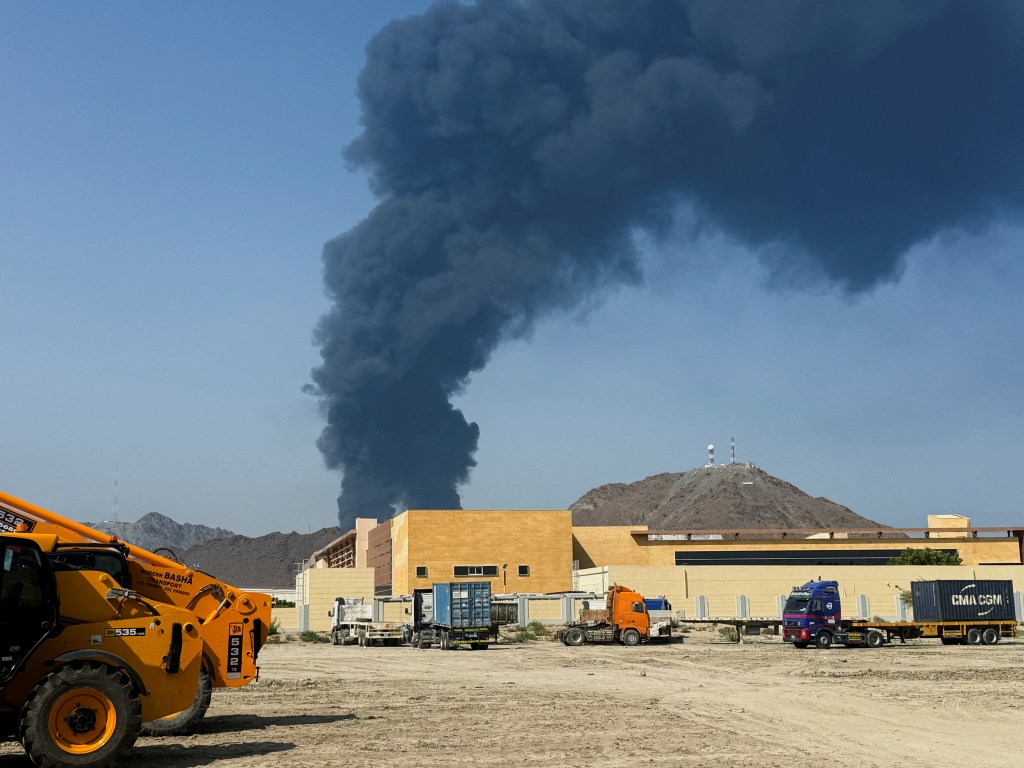 Thick black smoke rises above industrial buildings in the Fujairah oil industry zone, caused by debris after the interception of a drone by air defenses.