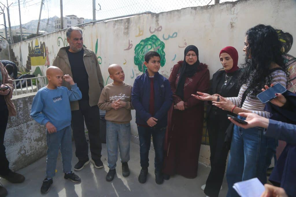 Zaid (center) stands next to his mother, Eman (right) while speaking to the press at his school in Nablus. (Photo: Ghassan Bannoura)