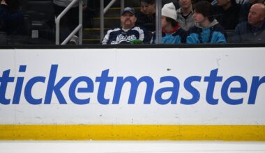 A large Ticketmaster logo on the boards inside an ice hockey arena.