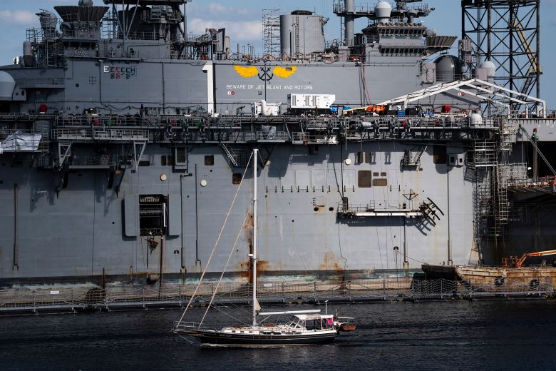 A sailboat passes a Naval ship in Portsmouth, Virginia.