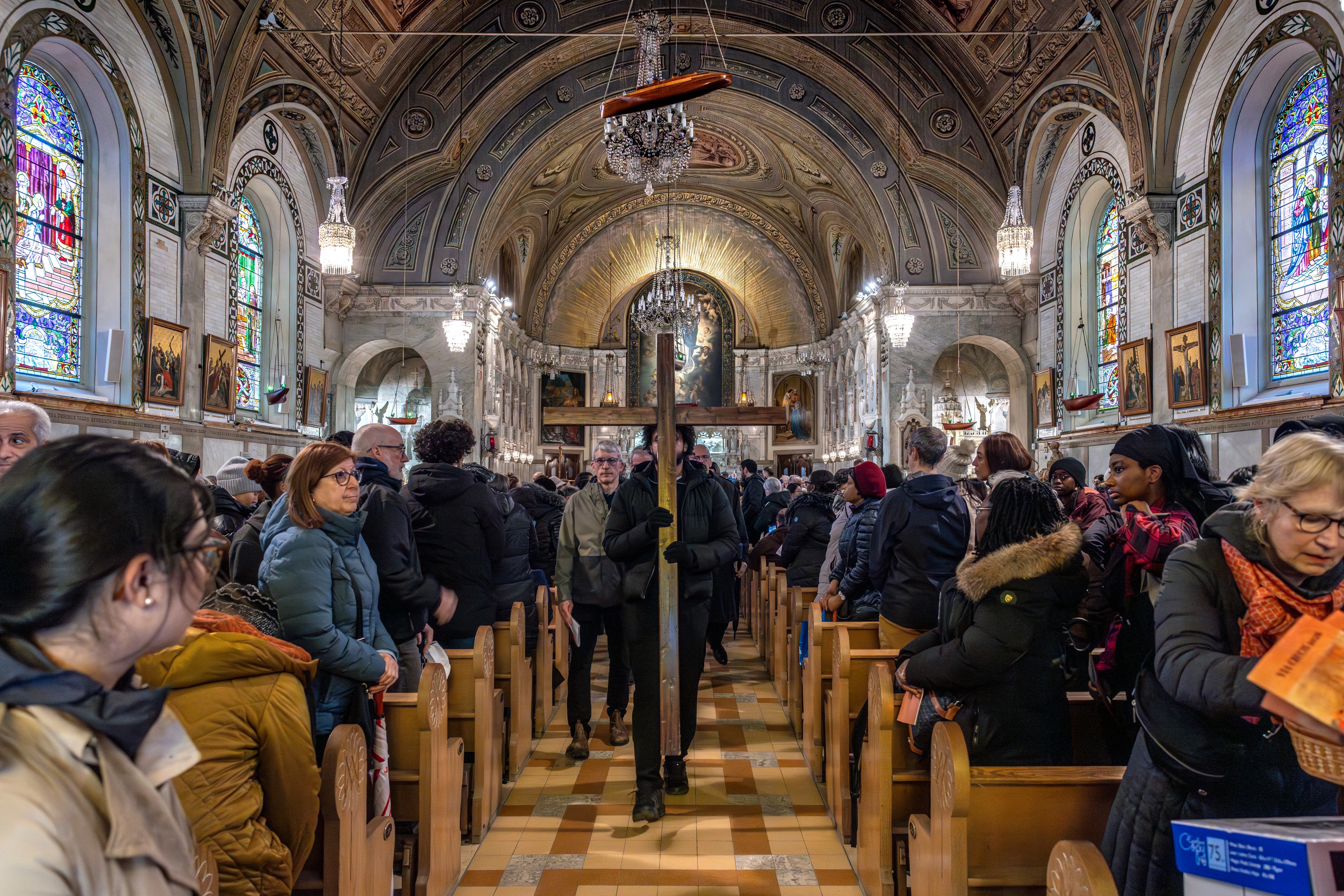 A man carries the cross down a church aisle.