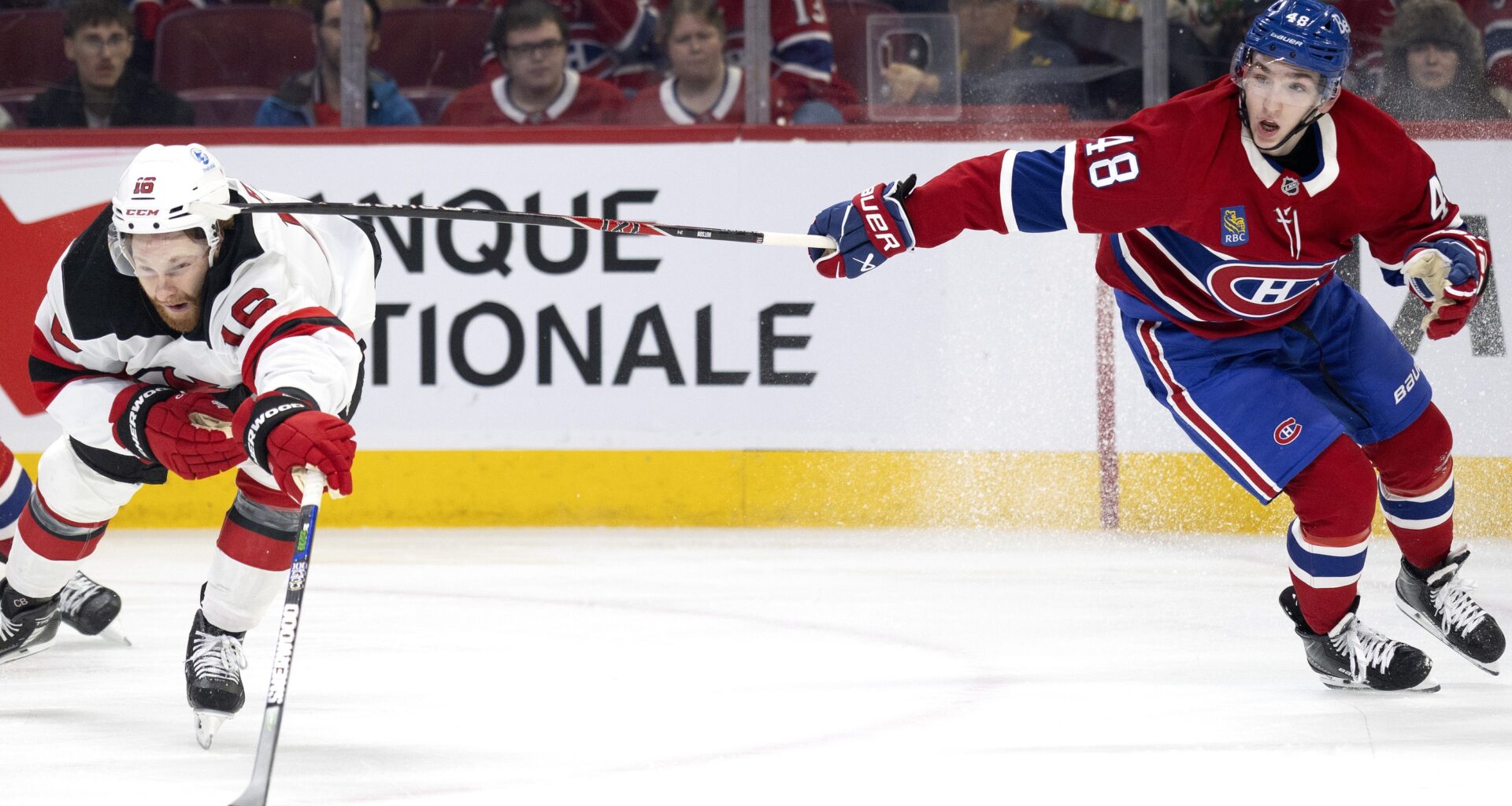 Canadiens defenceman Lane Hutson high-sticks New Jersey Devils winger Connor Brown during second period in Montreal on Sunday.