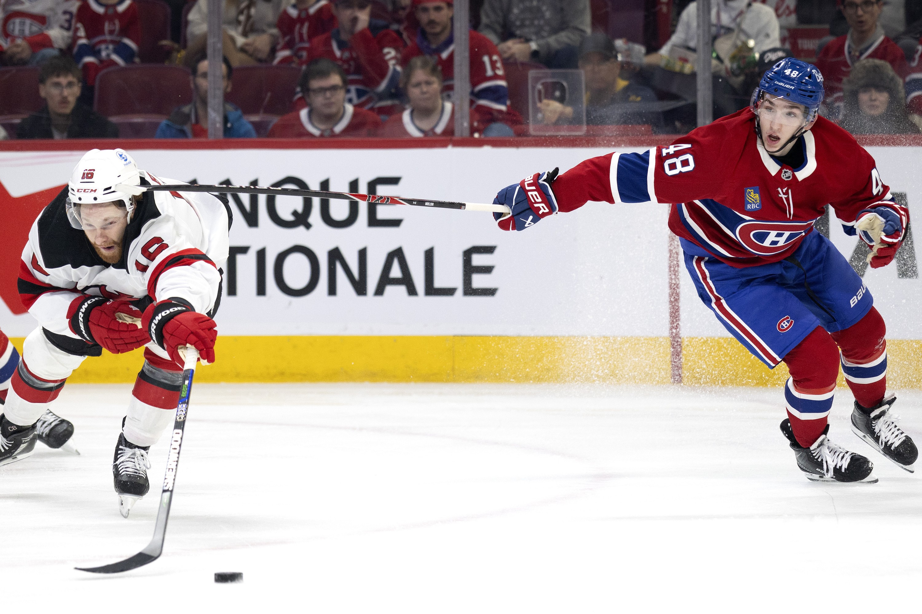 Canadiens defenceman Lane Hutson high-sticks New Jersey Devils winger Connor Brown during second period in Montreal on Sunday.