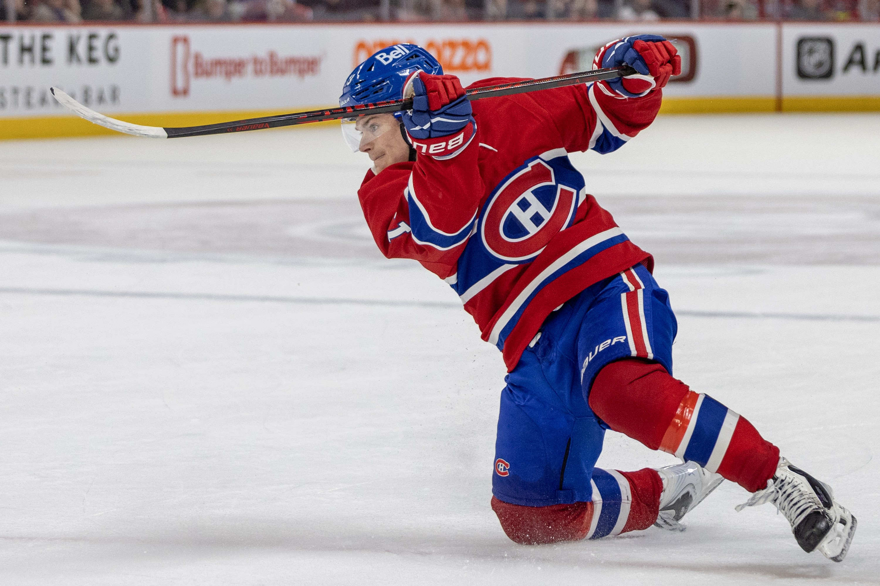 Cole Caufield follows through on a shot with one knee on the ice