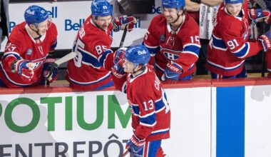 Hockey players on the bench congratulate a teammate skating by after he scored a goal.