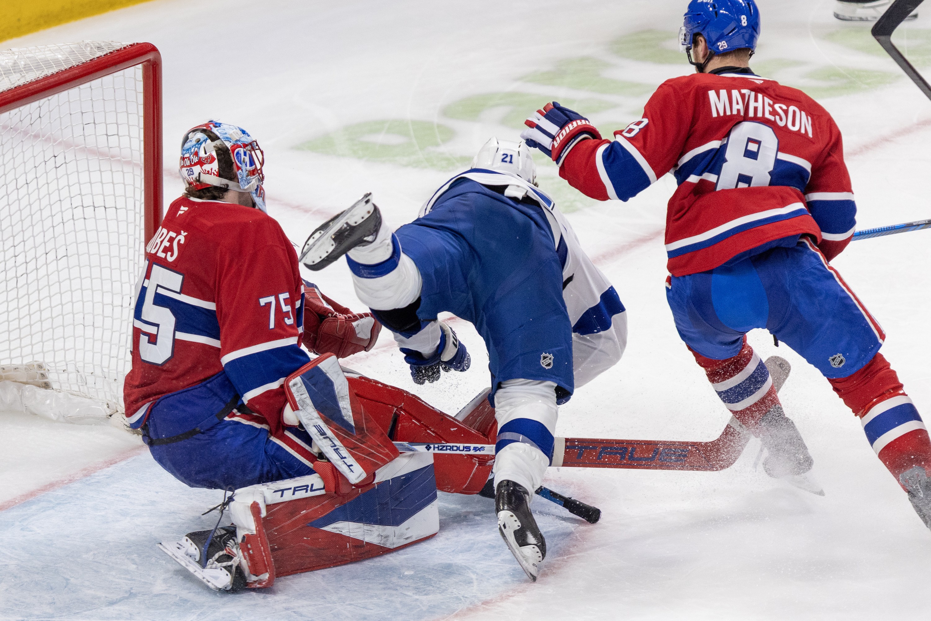 Hockey player crashes into the goalie. 