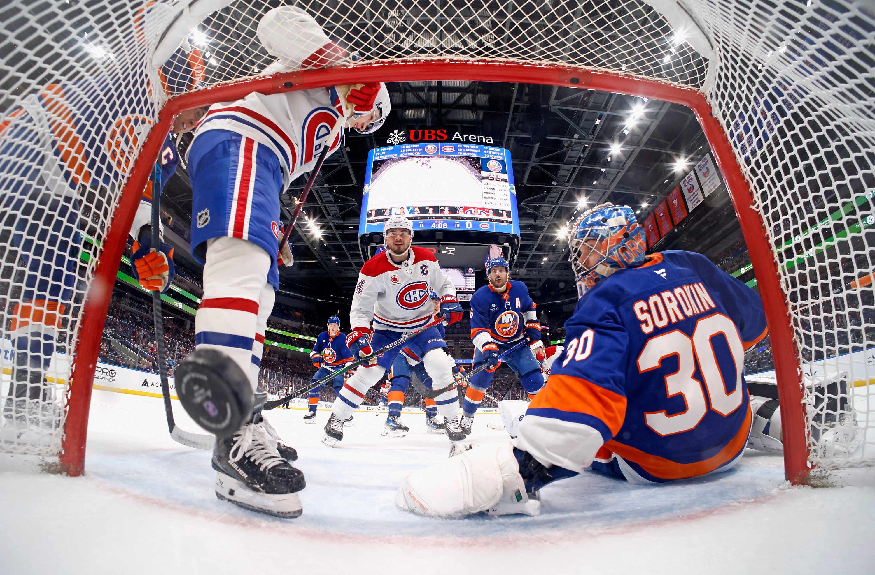 Canadiens captain Nick Suzuki, centre, scores a goal for his 100th point of the season during second period against Islanders' Ilya Sorokin on Sunday in Elmont, N.Y.