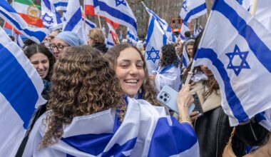 Two girls hug amid a throng of people carrying the Israeli flag.
