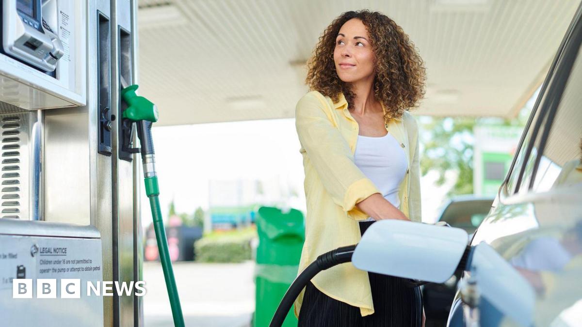 A woman wearing a white top and yellow shirt looks at a pump while filling up her car.