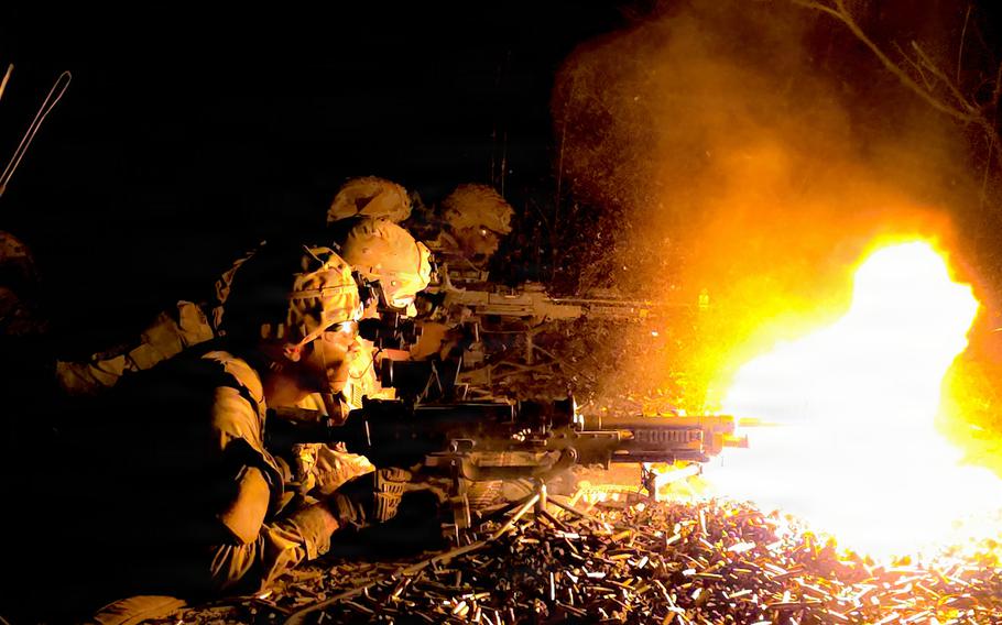 Soldiers in a prone position shoot machine guns.
