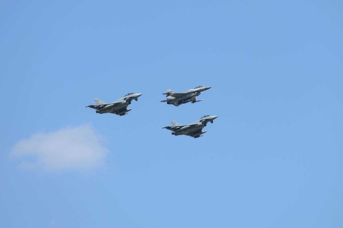 A Polish air force F-16 is flanked on either side by Eurofighter Typhoon fighter jets (file photo)