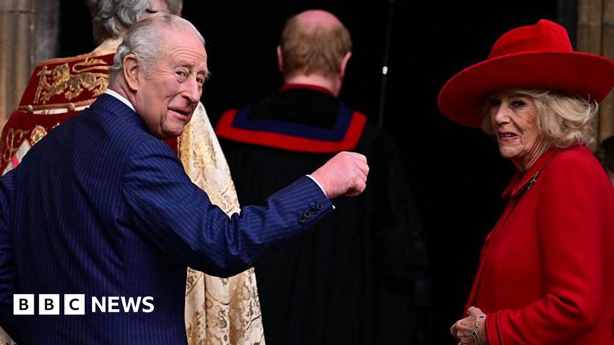 The King and Queen turn around to look behind them. The King holds a hand up while the Queen smiles