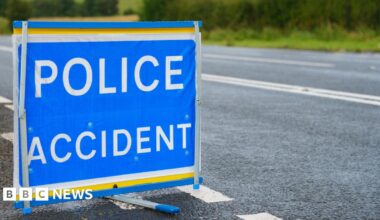 Blue police accident sign with white writing on the side of a road