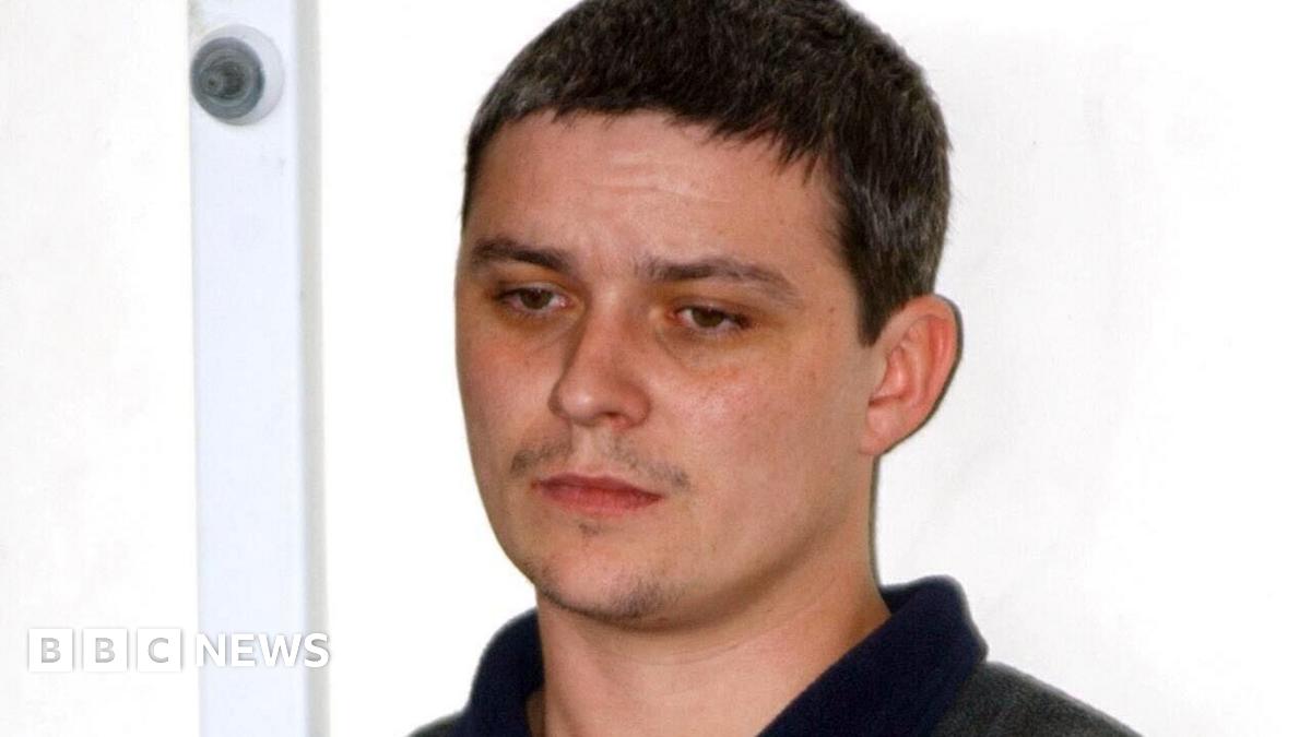 Ian Huntley stood in front of a white wall