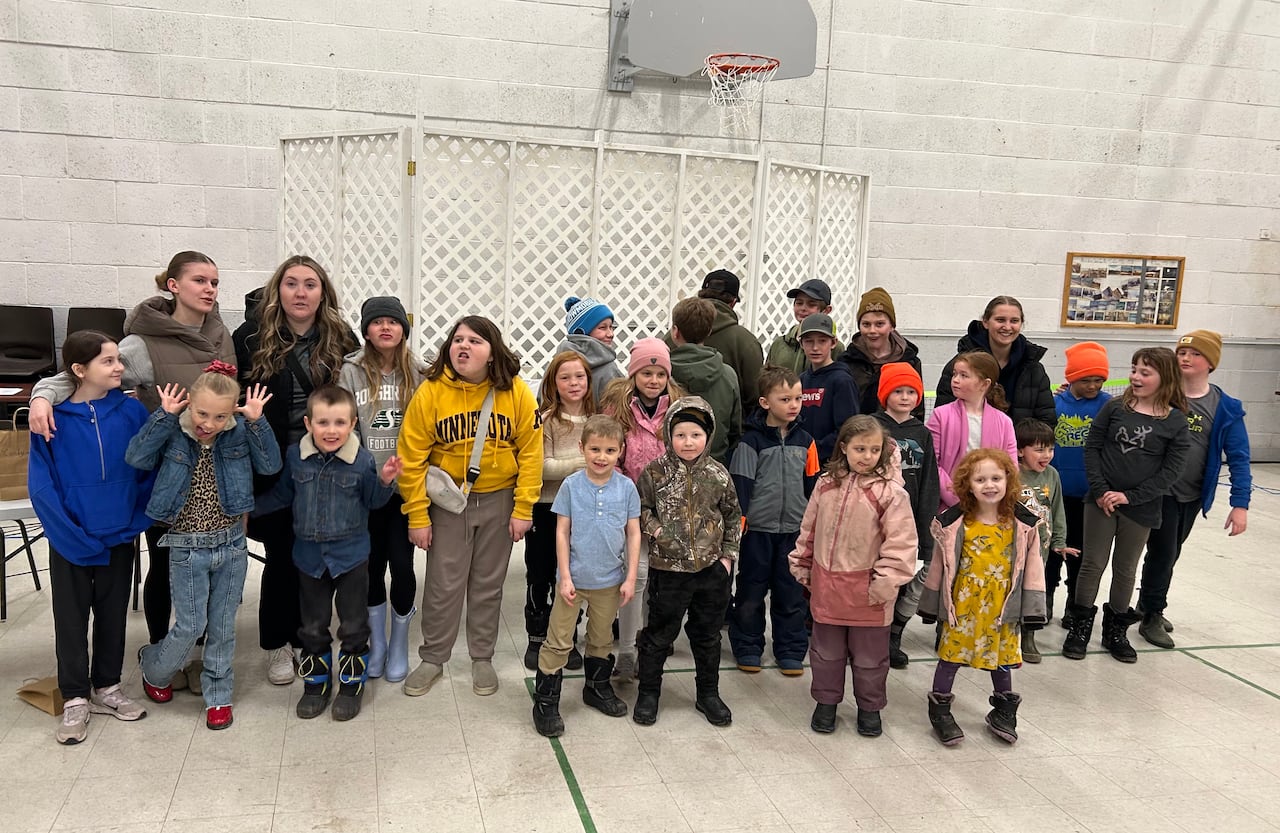 A large group of children and adults pose for a photo in a large indoor space.
